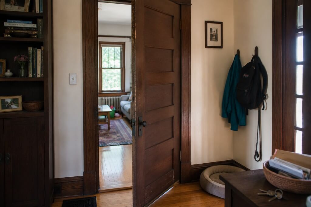Entryway with wood door, built-in bookcase, coat hooks, and hardwood floors